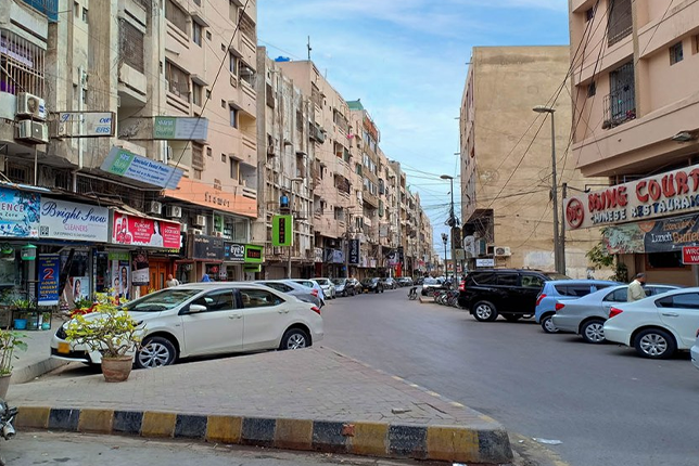 A row of closed shops in DHA Karachi, featuring shuttered windows and empty sidewalks.