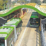 Green Line BRT station in Karachi with commuters boarding and alighting amidst a bustling atmosphere.