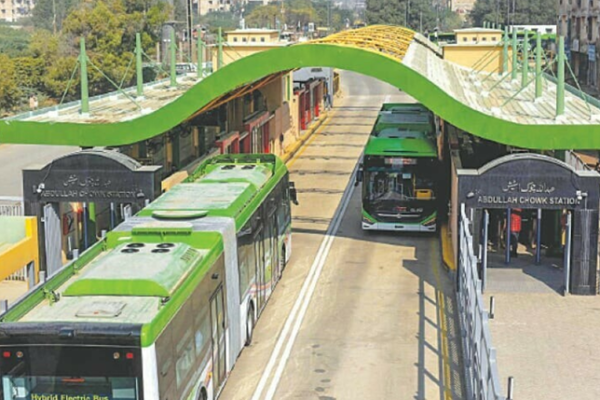 Green Line BRT station in Karachi with commuters boarding and alighting amidst a bustling atmosphere.