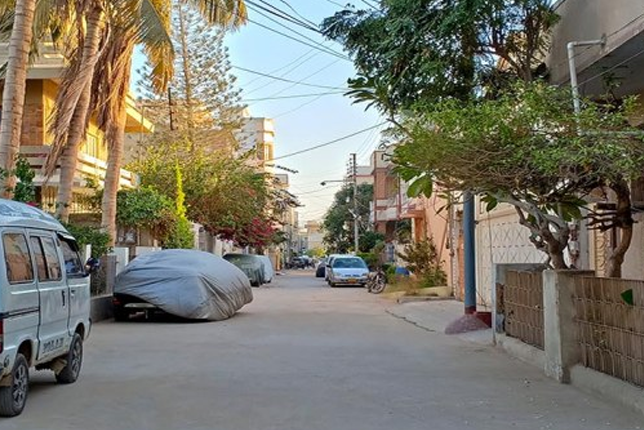 A quiet street in Sector 7-D/2, North Karachi, with residential houses and greenery.