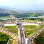 A scenic aerial view of the Swat Motorway surrounded by lush green mountains.