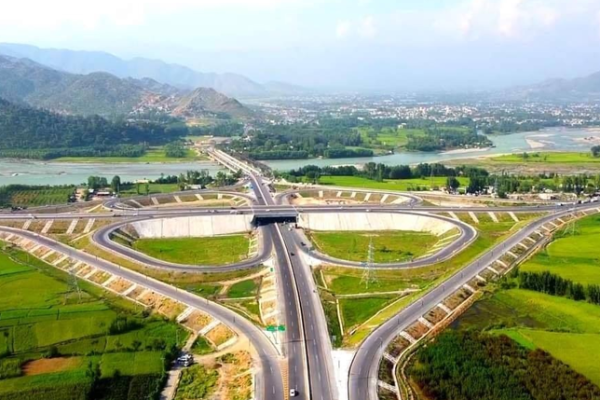 A scenic aerial view of the Swat Motorway surrounded by lush green mountains.