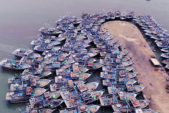 Traditional fishing boats docked at Fish Harbour Karachi under a clear blue sky.