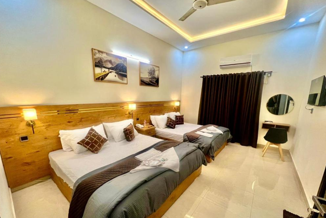 A well-furnished budget hotel room with a comfortable bed, TV, and workspace near Lahore Railway Station.