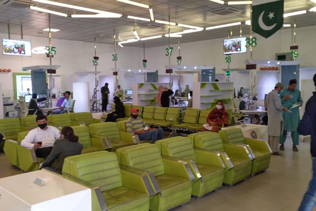 Citizens waiting at NADRA Multan office with a vendor serving chai nearby during golden morning hours